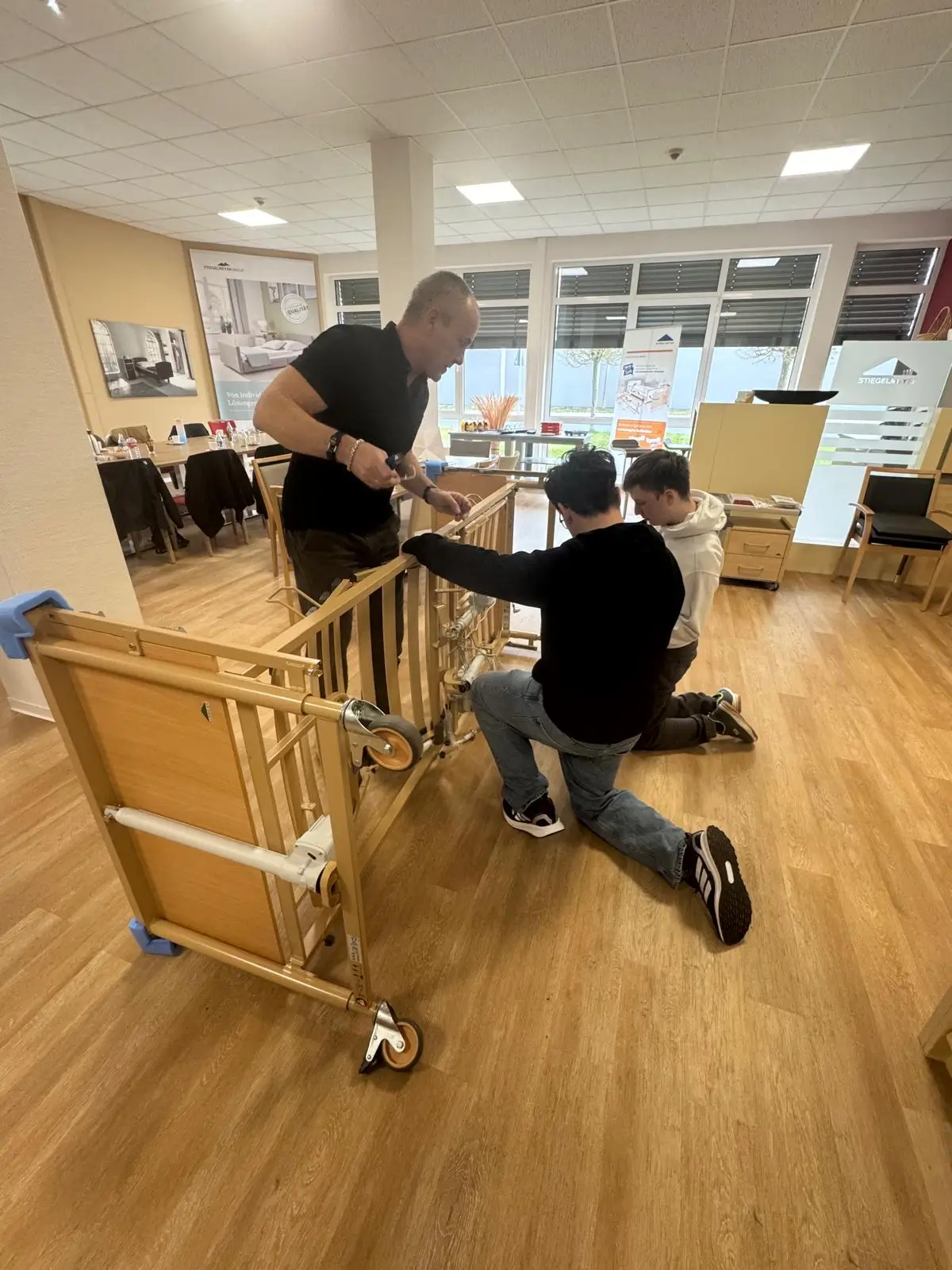 Azubis schrauben ein Pflegebett zusammen